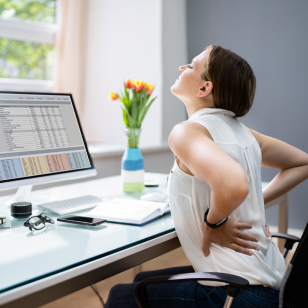 Woman sitting at a desk with lower back pain from bad posture